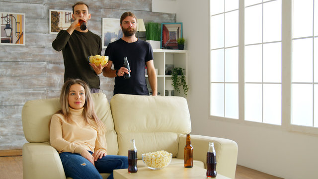 Group Of Friends Sitting On Couch Reaching Out For Pizza