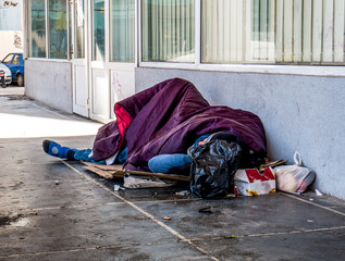Homeless man sleeping on the street and covered with blanket. Homeless man in Bucharest, Romania.
