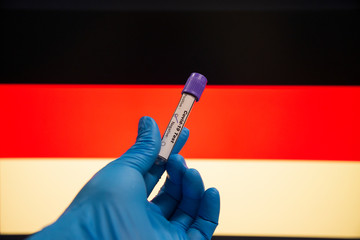 Coronavirus or Covid-19 in the Germany, sample blood tube in hand with Germany flag on background