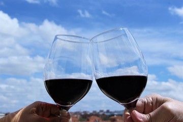 Two red wine glasses cheers up together drinking outdoor photo blue sky background copy space 