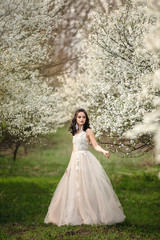 the bride in a wedding dress among the flowering trees holds a wedding bouquet, wedding day, beautiful portrait of a bride
