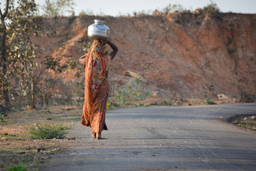 An Indian woman carrying a container of water on her head
