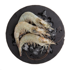 Fresh Vannamei shrimps, whiteleg shrimp, Pacific white shrimp or king prawn on black slate board isolated on white. Top view, close-up.