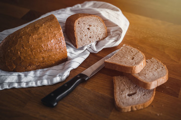 Rustic crusty loaves of bread on wooden plate. Bakery concept with cut sliced homemade bread....