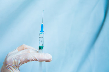 Hands in white gloves hold a syringe on a blue background. Coronavirus disinfectants, asian flu outbreak, Coronavirus 2019-nCoV, Corona virus outbreaking. Spray bottle