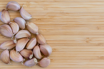 a lot of unpeeled garlic cloves on a bamboo board