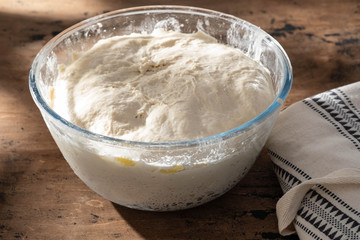 bowl of fresh raw dough on wooden background