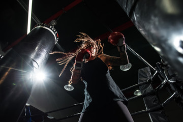 Girl boxing punching bag with dreadlocks and tattu. Beautiful boxer girl with artistic flare . Sports girl .
