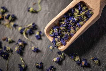edible viola violeta odorata dry dried purple flower blossom bud heads for tea on a wooden spoon on...