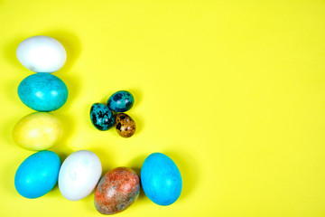 Multicolored, painted Easter eggs on a yellow background. space for text