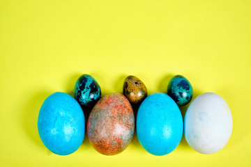 Multicolored, painted Easter eggs on a yellow background. space for text