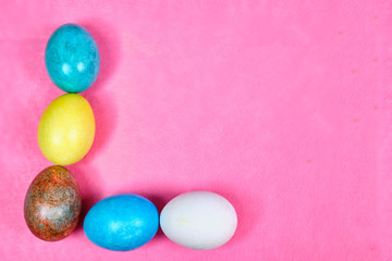 Multicolored, painted Easter eggs on a pink background. space for text