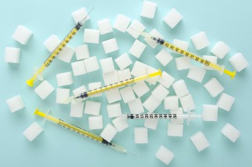 Top view of sugar cubes ad insulin syringes on the blue surface.Concept of insulin injections for...