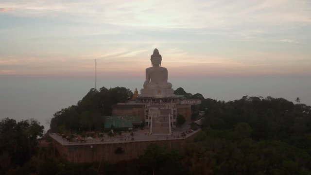 Slow pan around monument of The Great Buddha of Phuket, located on top of the  Nakkerd Hill, with blueish and pinkish clouds on horizon on the sunset, Phuket, Thailand.