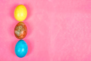 Multicolored, painted Easter eggs on a pink background. space for text