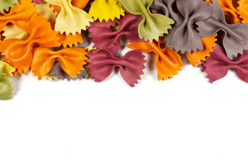 Obraz premium Italian raw multicolored farfalle pasta on white background with copy space. Colorful pasta in bow tie shape. Italian cuisine concept. Mockup for design.