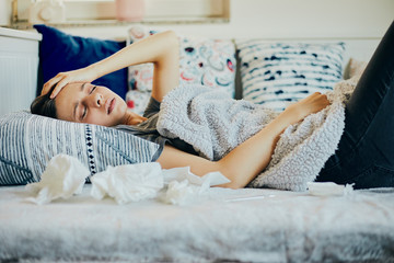 Sick woman lying in bed with cold, flu and high fever.
