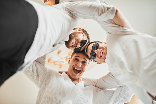 The groom is going to the wedding. Photosession of three energetic guys at the hotel. Brown tones.