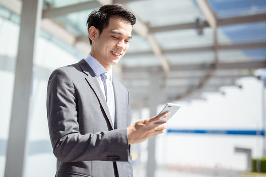 Asian business man using on smart phone traveling walking inside in airport.