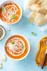 Pumpkin and carrot soup with cream and basilic on blue stone background Top view
