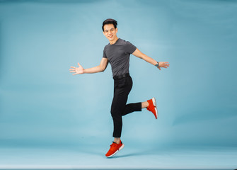 Fototapeta na wymiar Hnadsome Asian man jumping isolated over blue wall background. 