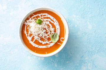 Pumpkin and carrot soup with cream on blue stone background.