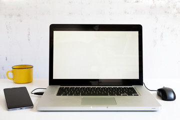 Fototapeta premium laptop with mouse, smartphone and yellow cup