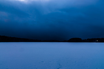 night landscape with a frozen lake and sky tightened clouds