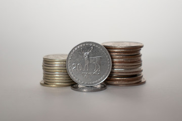 tetri and lari coins on a white background are next to other coins piled in a column