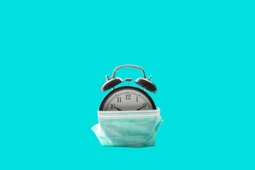 Alarm clock and medical mask on azure background