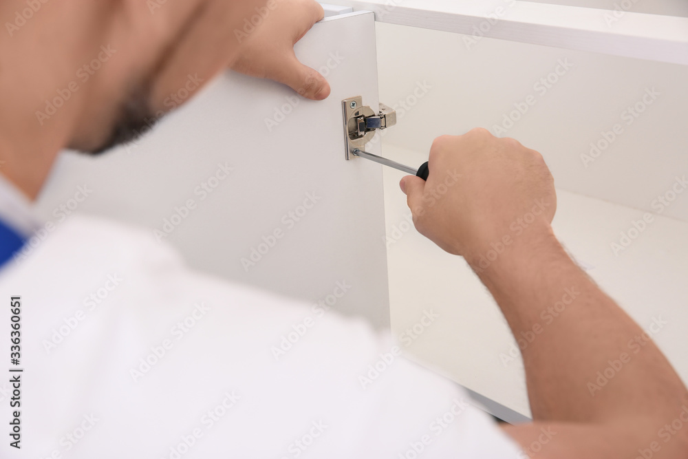 Sticker Worker installing door of kitchen cabinet, closeup