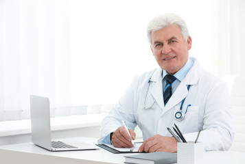 Portrait of senior doctor in white coat at workplace