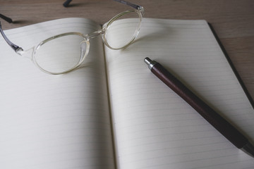 notebook and pen and glasses on the table