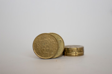 a coin worth fifty euro cents stands upright next to the other coins lying one on one on a white background.