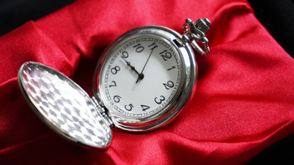 Old antique pocket watch showing time on red velvet. Close up
