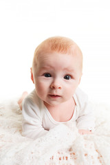 a small 4 month old baby lies on a soft light blanket and looks at the camera. Adorable baby isolated on white.