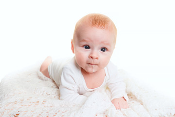 a small 4 month old baby lies on a soft light blanket and looks at the camera. Adorable baby isolated on white.