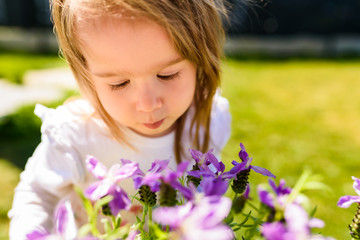 Portrait of 2 year old sweet girl outside, sunny spring day in backyard.