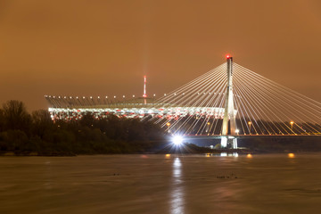 Modern illuminated bridge in Warsaw - capital of Poland and National Stadium.