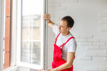 Worker in overalls setting up new windows in the office