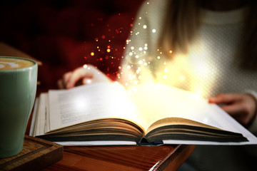 Woman reading shiny magic book, closeup view