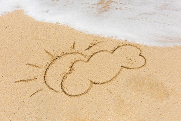 Sun and cloud sign and wave on a sandy beach. Background close up.