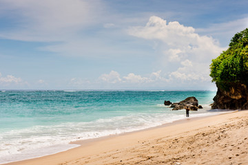 A young man is standing on the beach and is fishing. Pandawa beach, Bali, Indonesia.