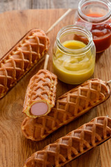 Waffle corn dogs on wooden background. Trendy street food