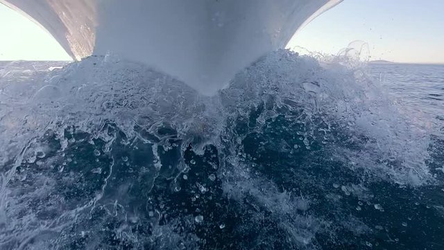 Low Angle View Of Bow Of Boat Slicing Through Water Creating Wake. Slow Motion.