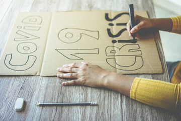 Young woman preparing a banner for Covid 19 economic crisis protest - Coronavirus world pandemic...