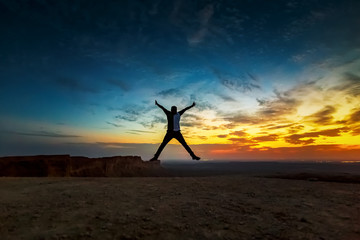 Happy Man jumping silhoutte poses with beautiful sunset background in Edge of the world Riyadh Saudi Arabia. Selective focused on the subject.