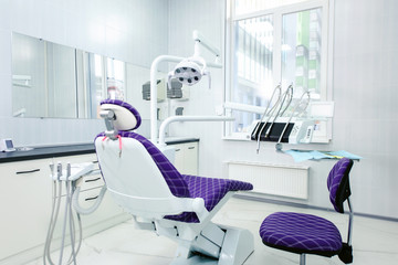 Interior of a modern dental clinic. The dentist's chair is ready to go. Special medical equipment in a white medical light