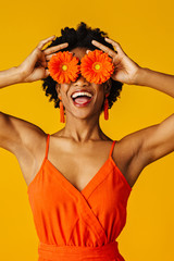 Portrait of a an excited young woman with orange gerbera daisies covering her eyes