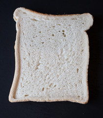 A slice of white bread on a black background